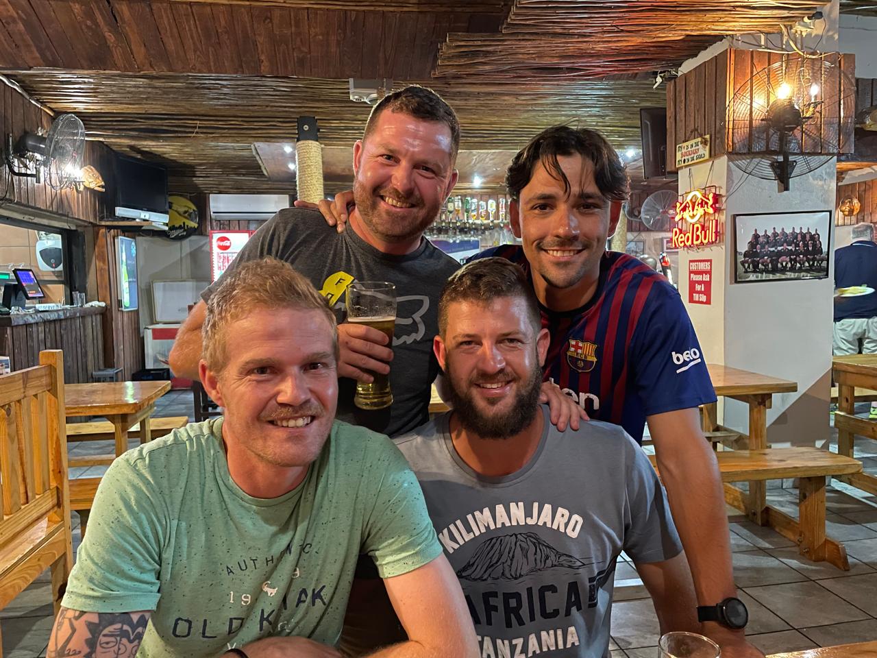 Four friends laughing together at a wooden pub table