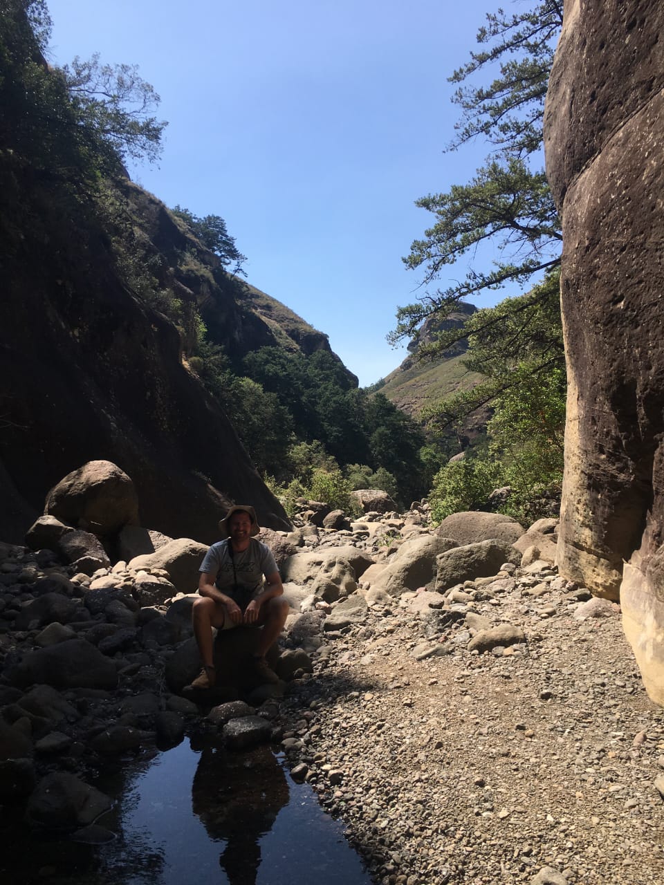 Angelo crouching among the boulders of a rocky mountain gorge