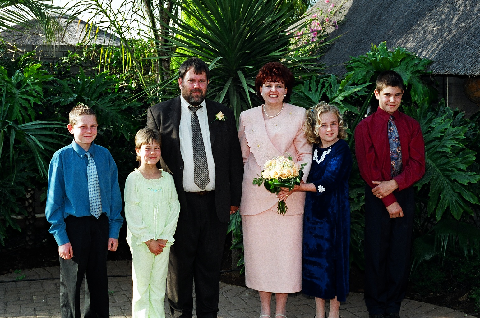 A family wedding group portrait with the bride, groom and children in a garden
