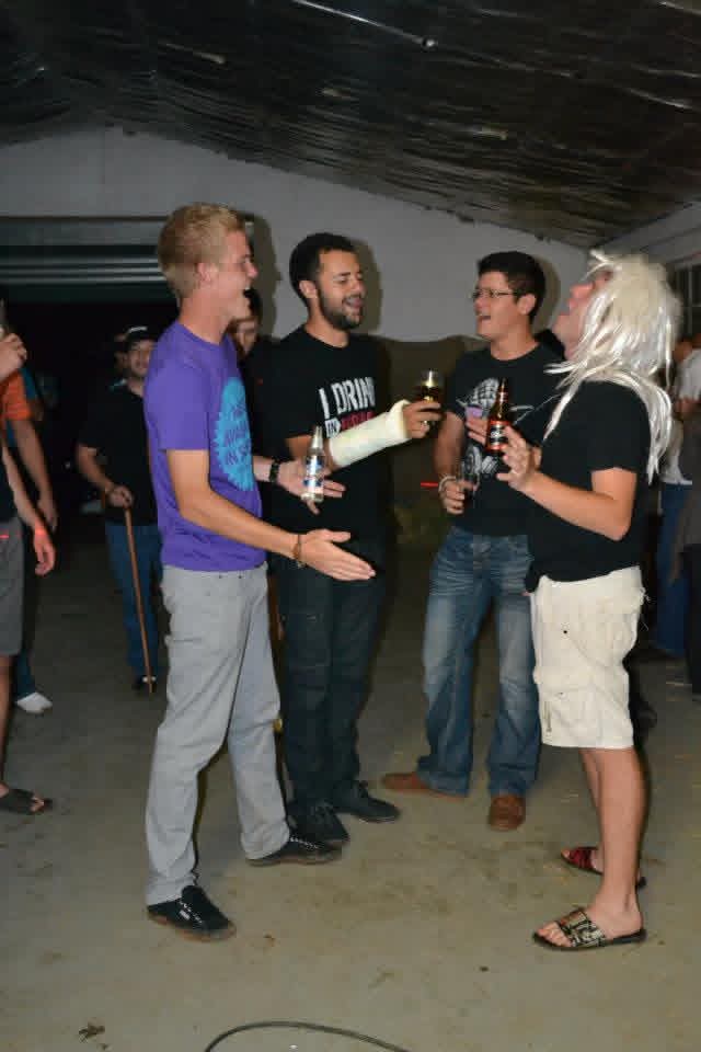 Four friends laughing together with drinks during the party