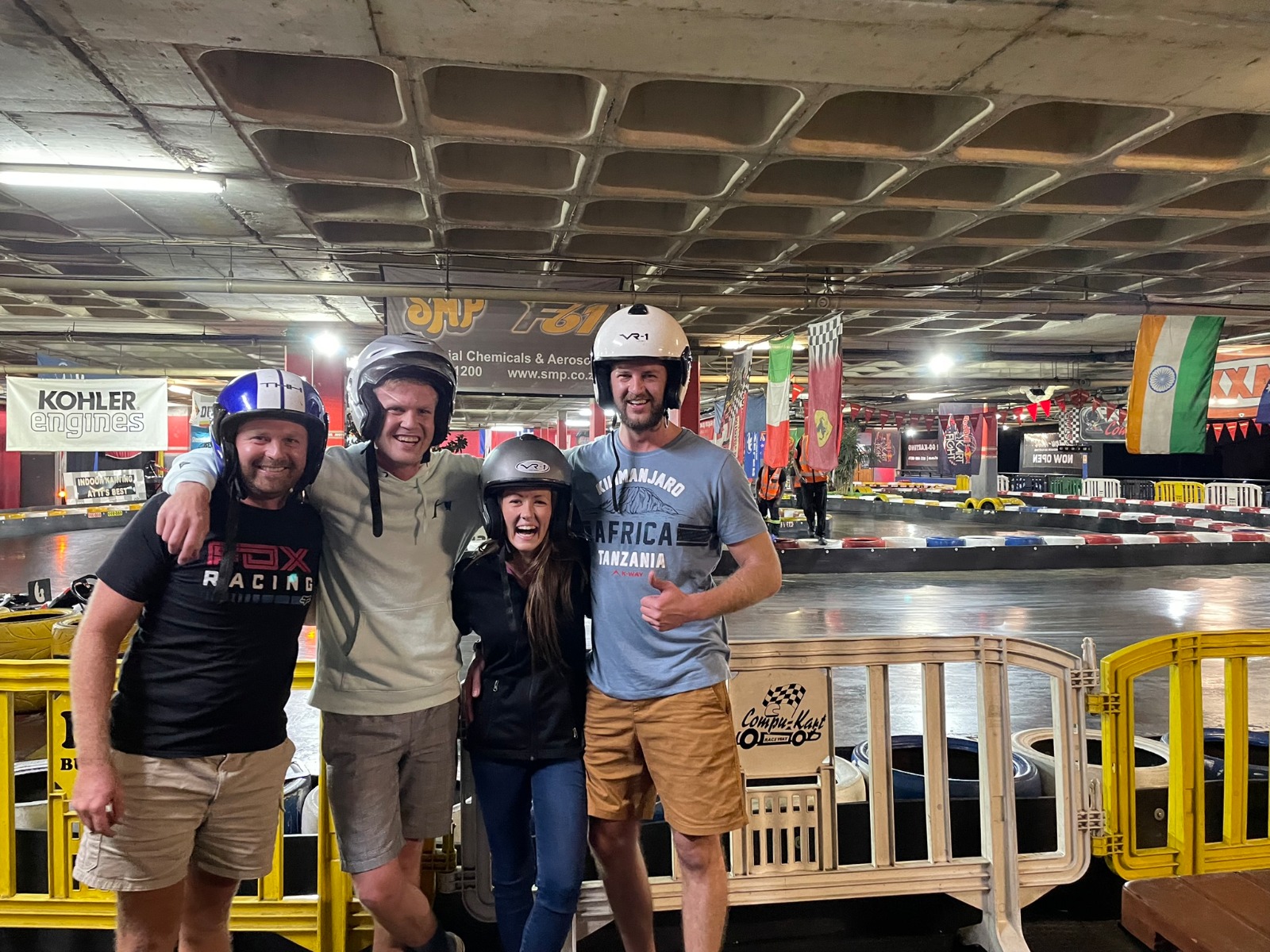 Four friends in helmets at an indoor go-kart track