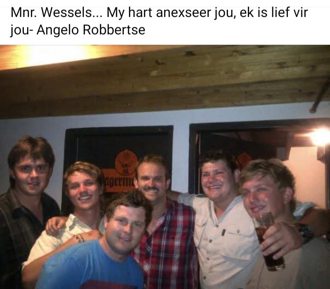 Six friends posing together inside a pub with a Jagermeister sign behind them
