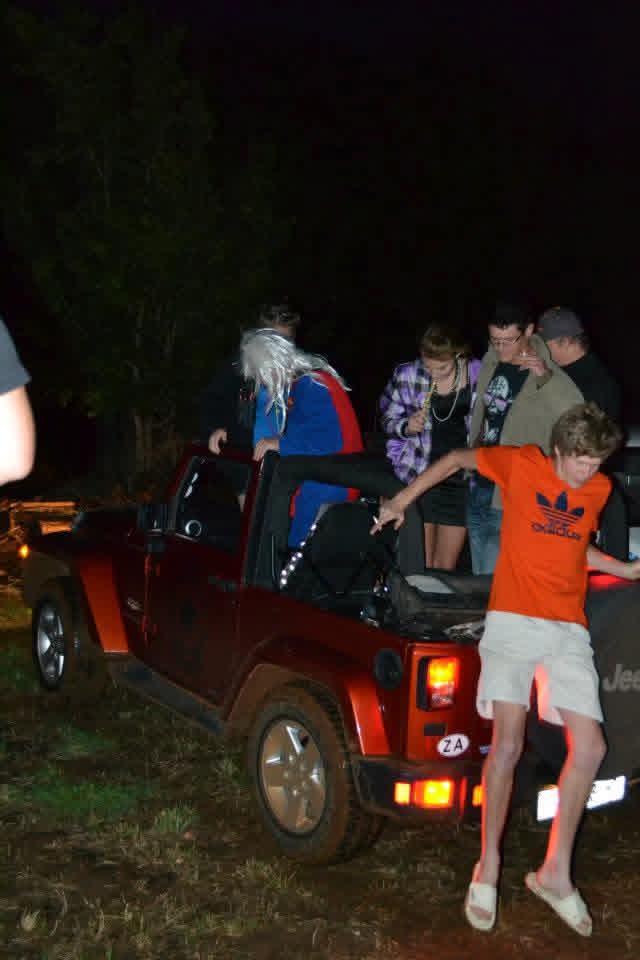 Friends on the back of a red jeep at night during the party