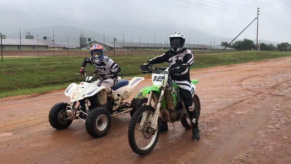 Angelo on his quad bike and his friend on the green dirt bike standing side by side in full gear