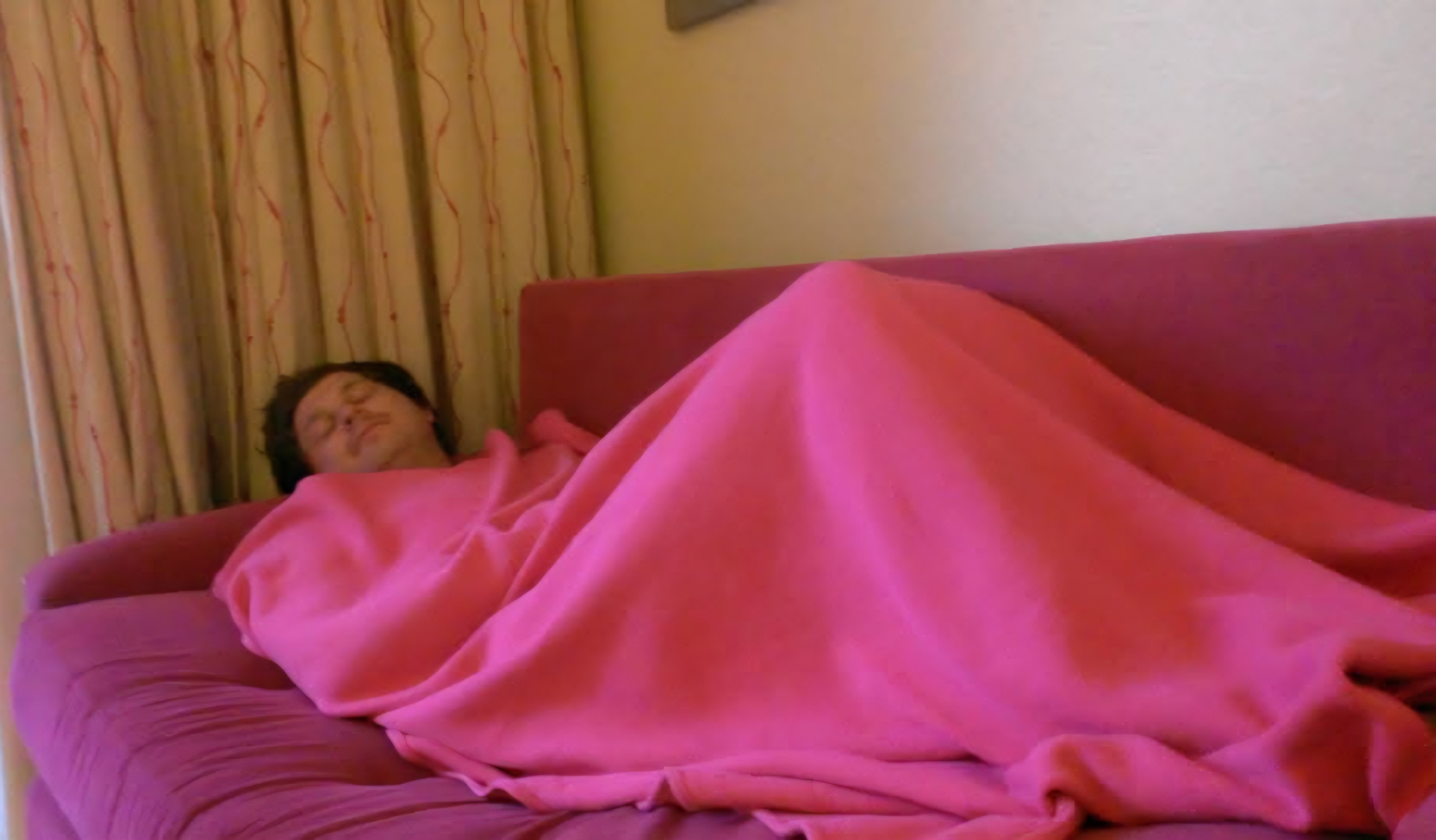 Angelo sleeping under a bright pink blanket