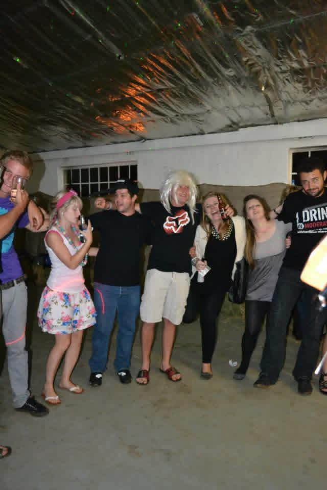 Angelo in a white wig celebrating with friends in the party hall