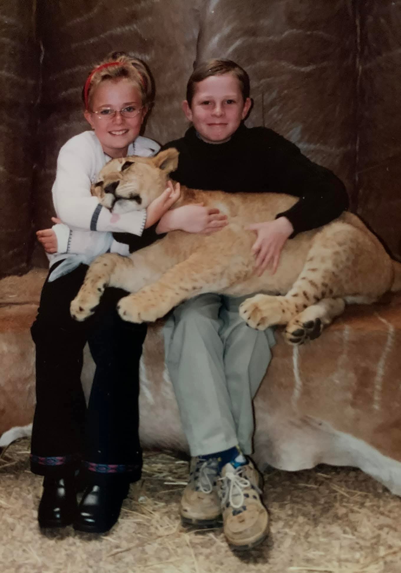 Young Angelo and a girl seated together holding a lion across their laps