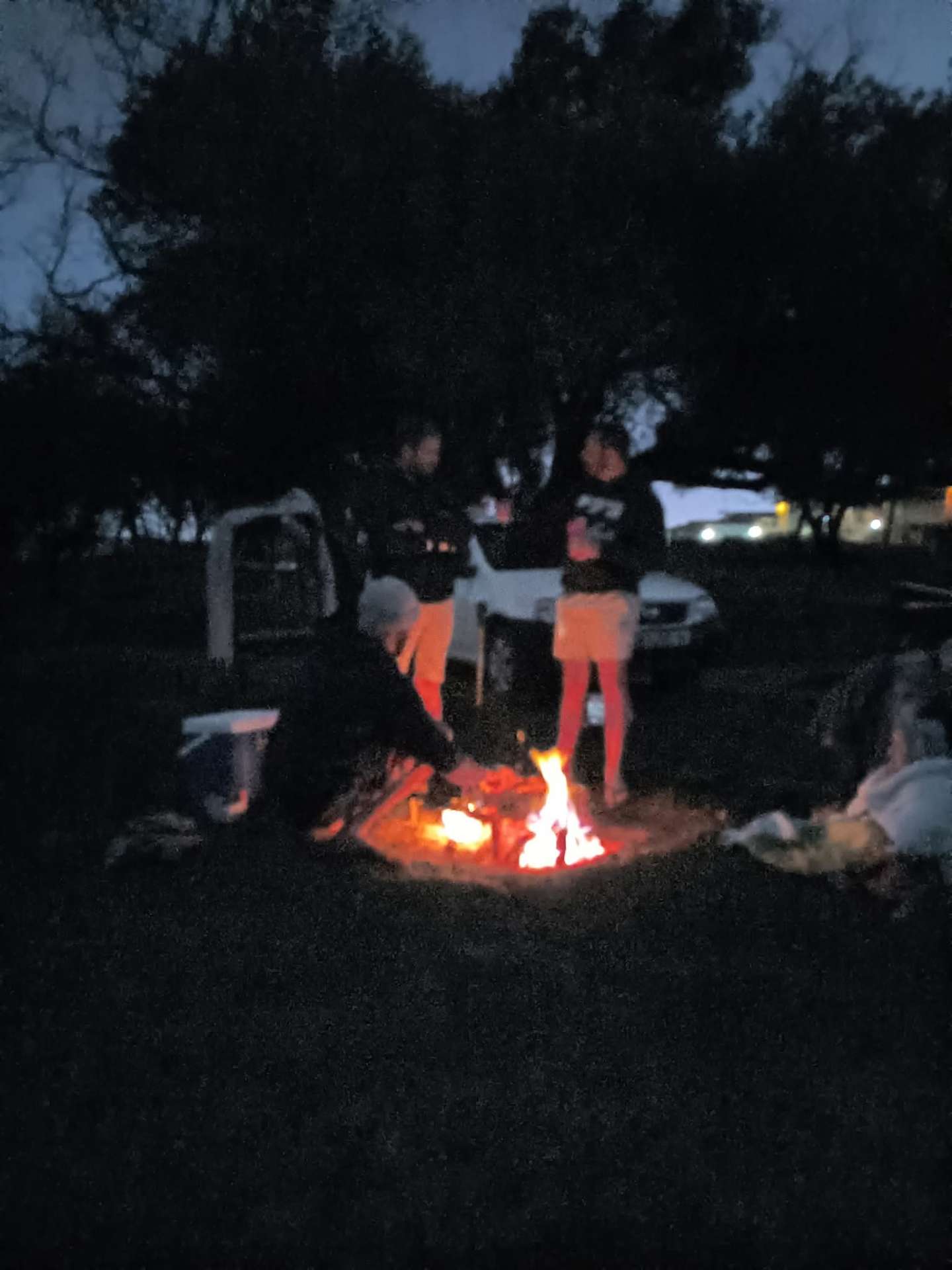 Friends gathered around a campfire at night in a campsite