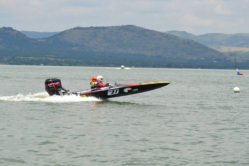 The black number 21 boat gliding across calm lake water with hills behind