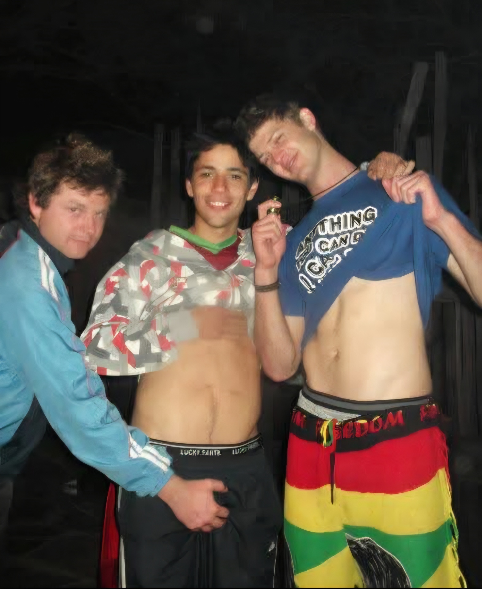 Three friends standing together indoors with arms around each other