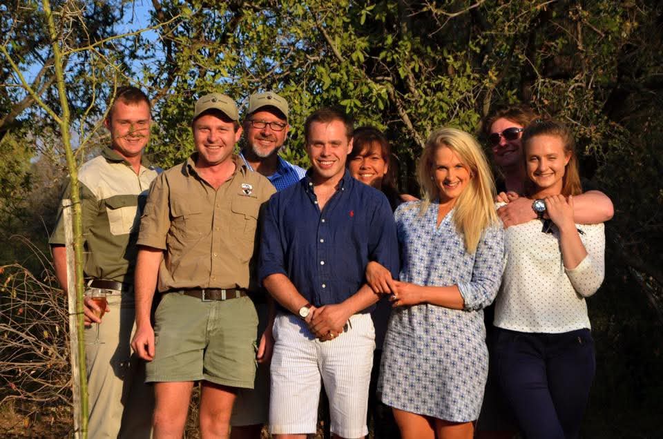 Angelo with a group standing beneath trees in warm evening light