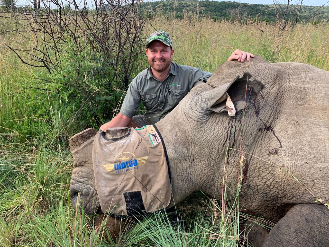 Angelo beside a sedated white rhino wearing a protective eye mask during a procedure