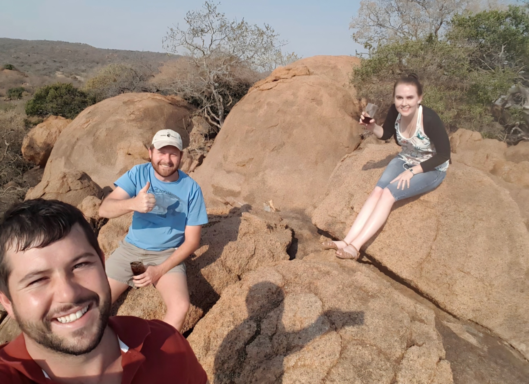 Friends relaxing on large boulders in the bushveld at sunset