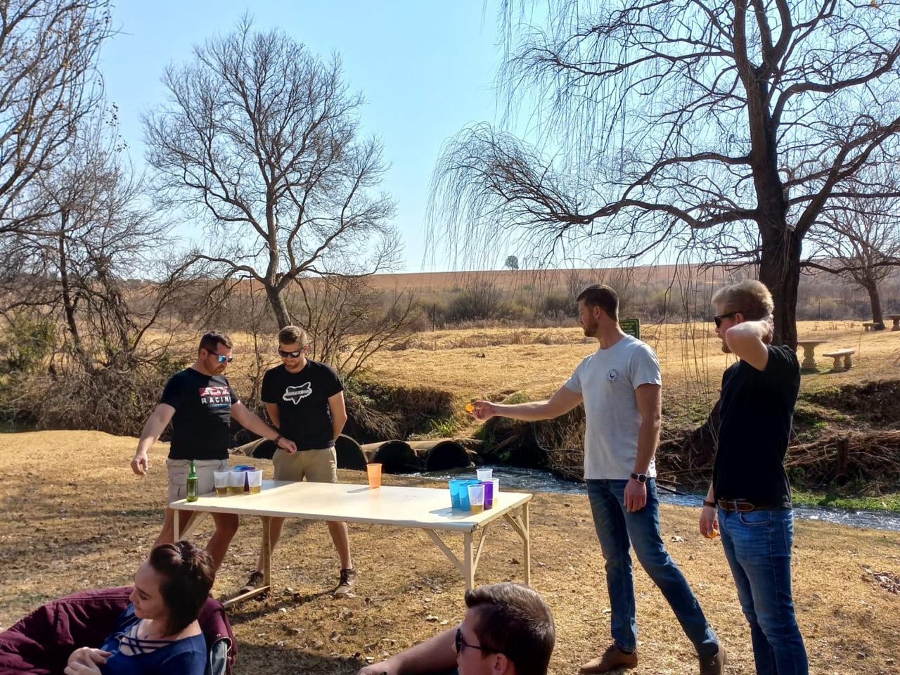 Friends playing a game beside a folding table on a dry riverbank
