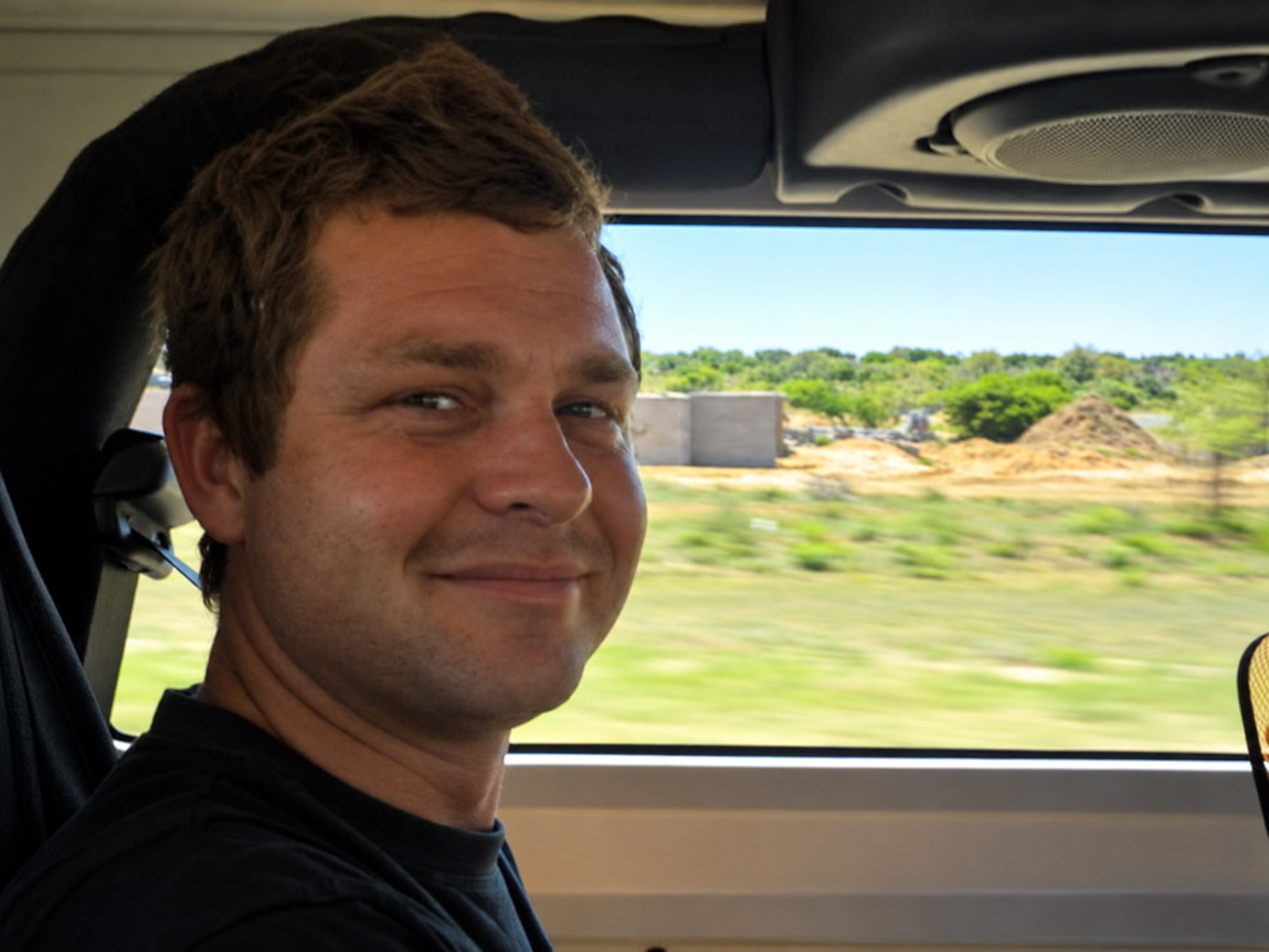 Close portrait of Angelo smiling while sitting in a vehicle