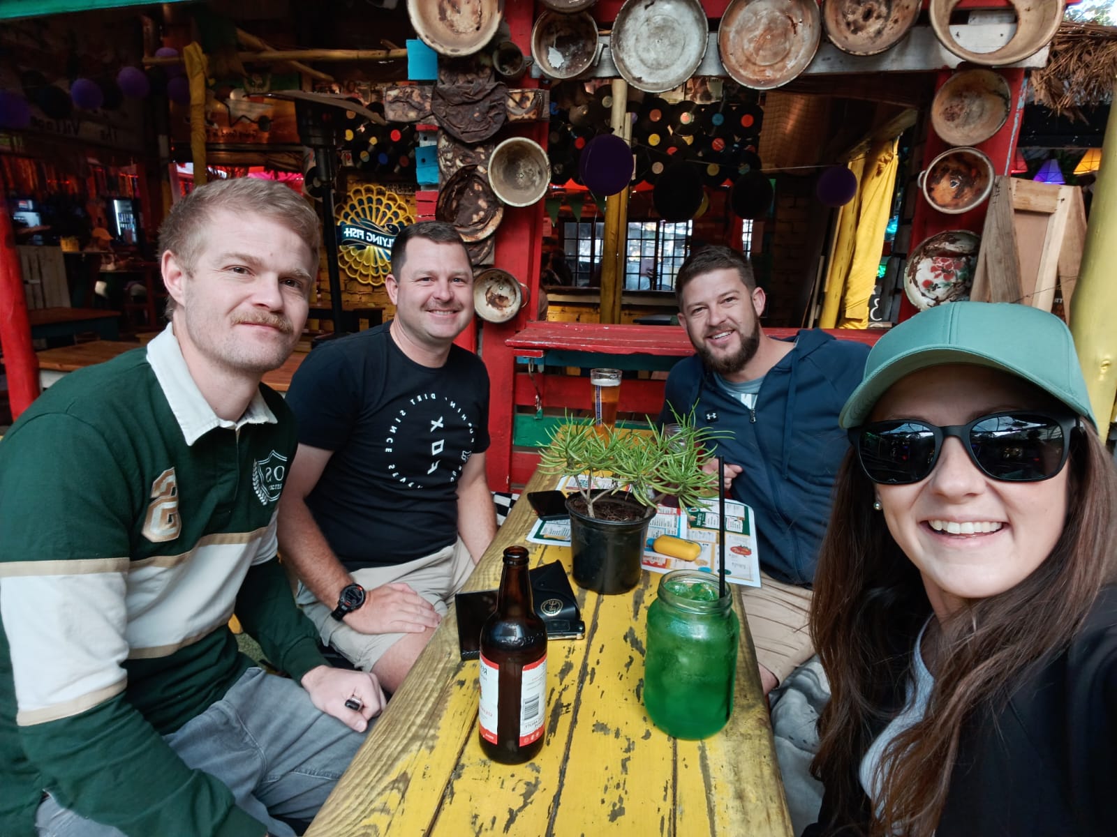 Friends gathered around a colourful outdoor table taking a selfie