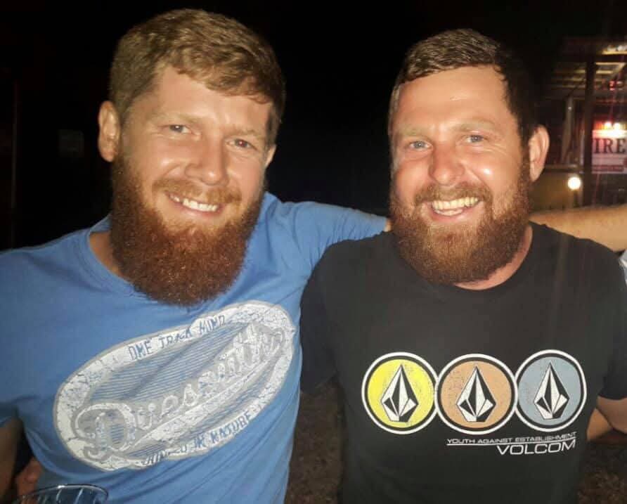 Two bearded friends smiling together at night