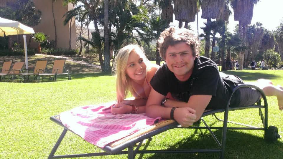 Angelo and a friend relaxing together on a garden lounger beneath palms