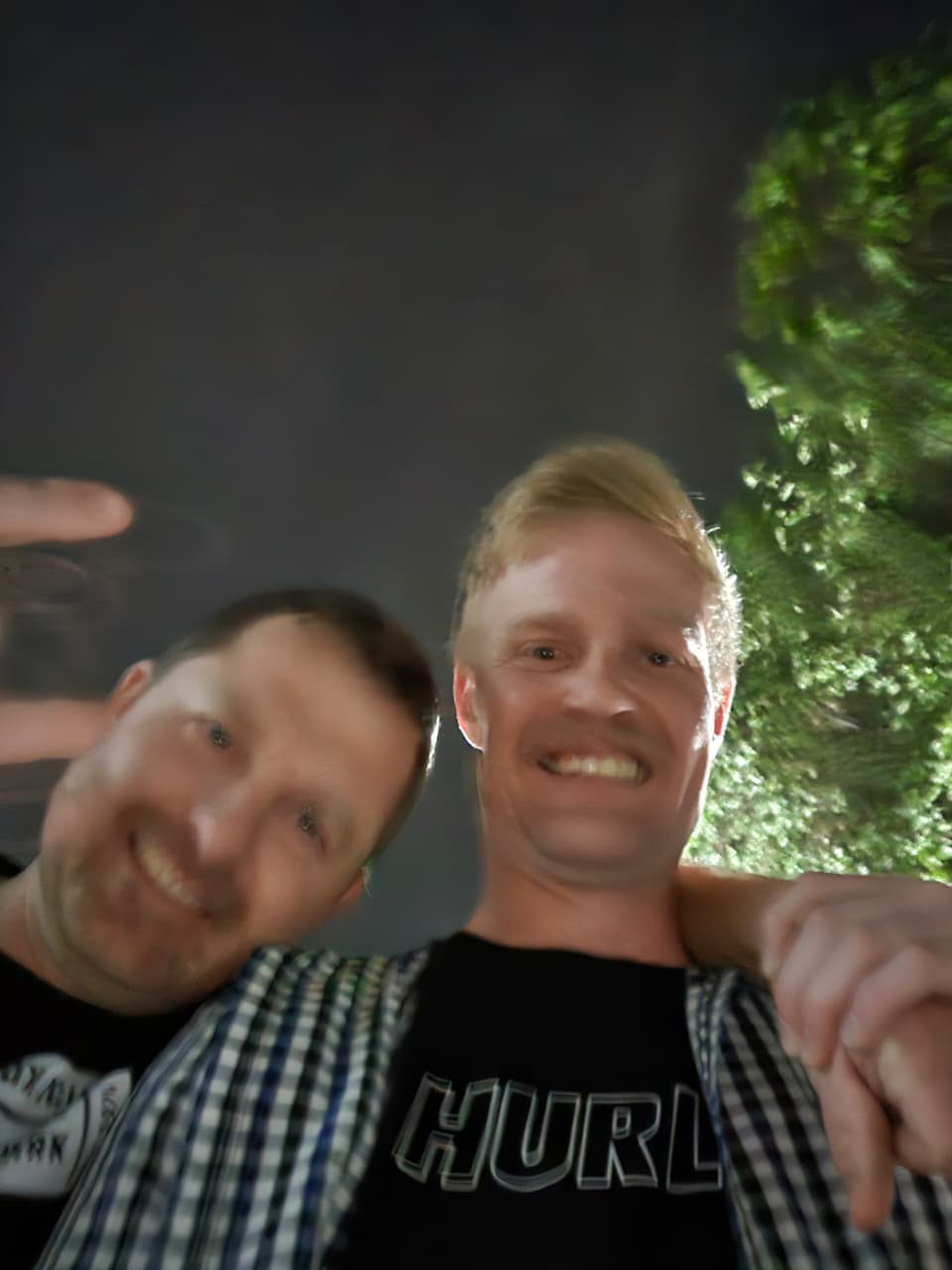 Angelo and his friend laughing together in a close selfie at night