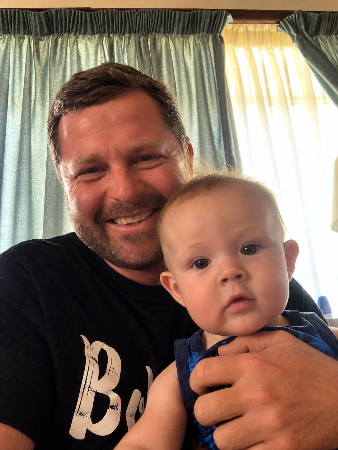 Angelo smiling in a selfie holding a baby
