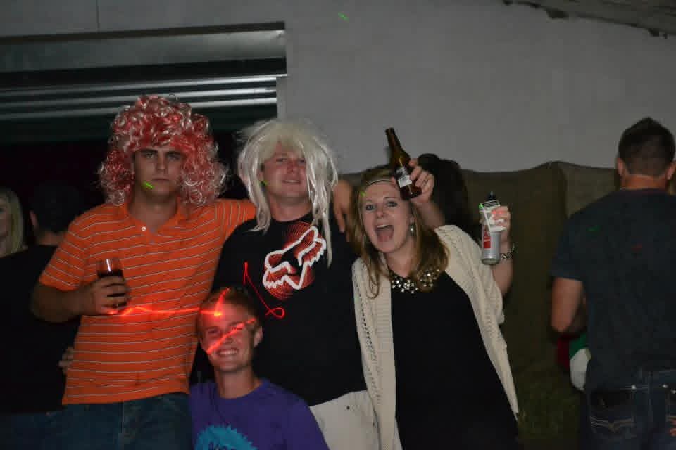Friends in fancy-dress wigs posing together at the party