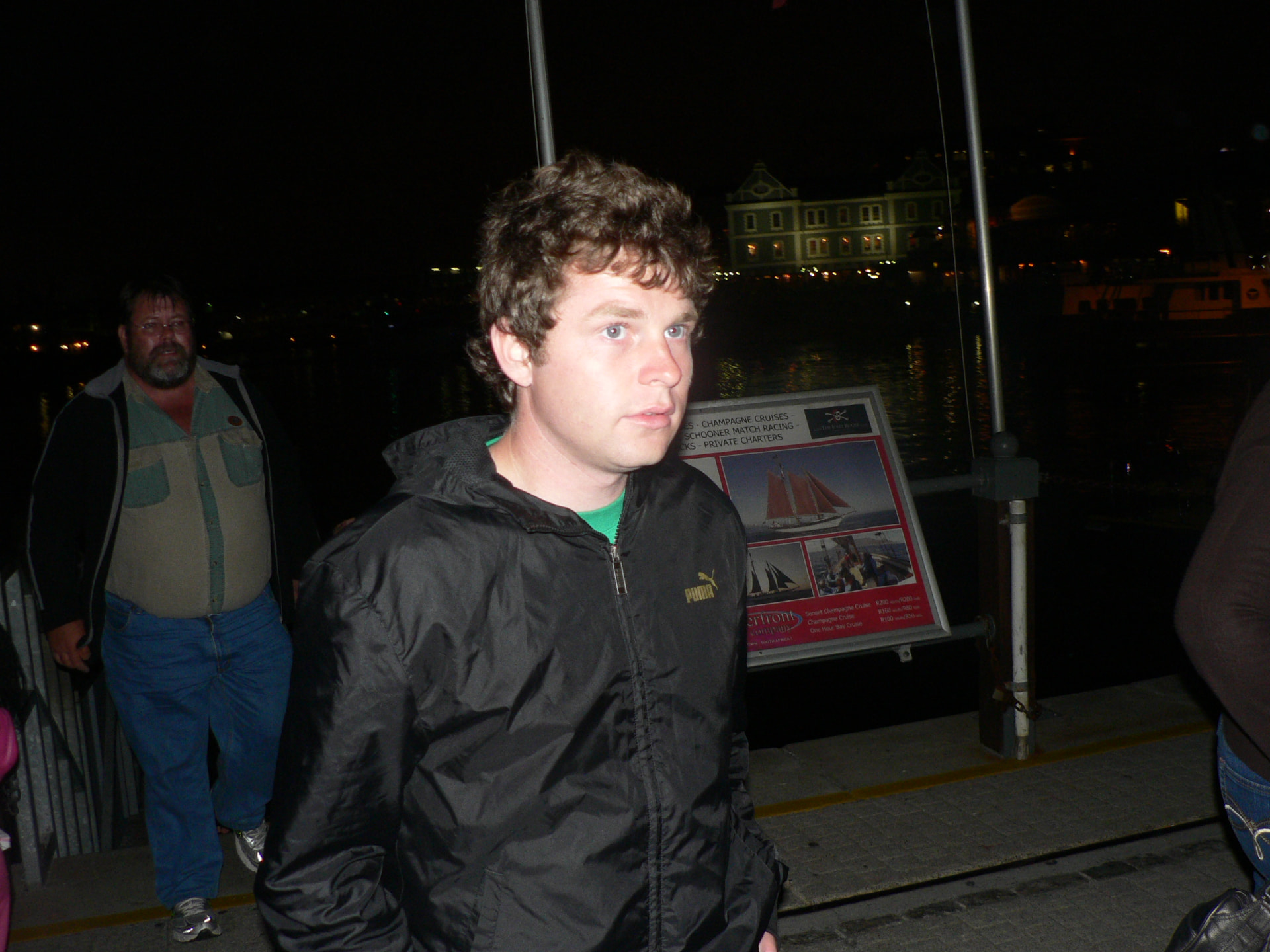 A young Angelo with family at the harbour at night, wearing a black jacket