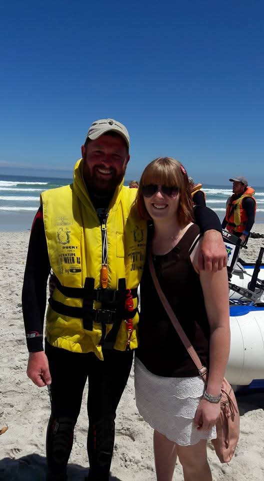 Angelo and a woman together beside an inflatable boat on the beach