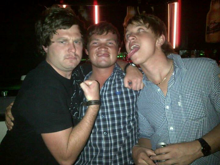 Three friends pulling faces together on a night out under red neon lights