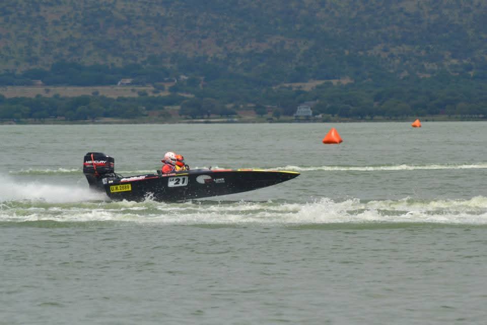 The number 21 boat running past orange course buoys on calm water