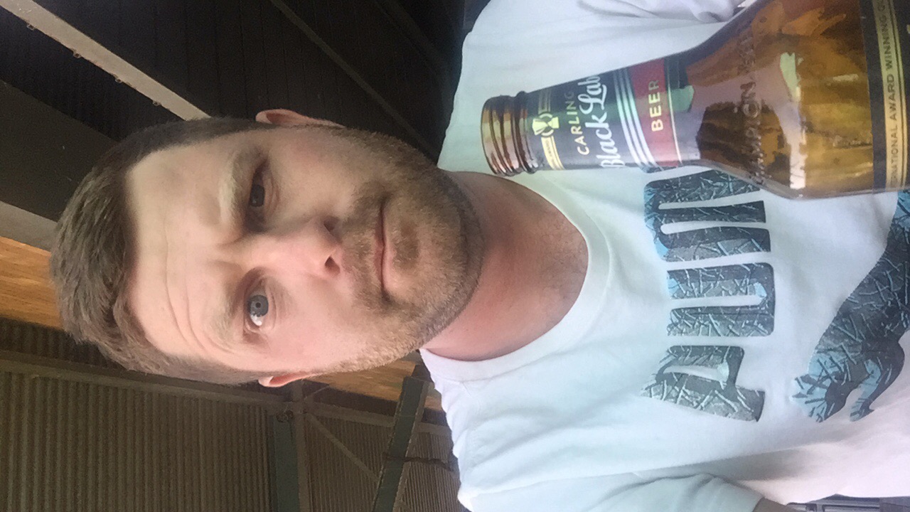 Angelo taking a selfie holding a Carling Black Label bottle
