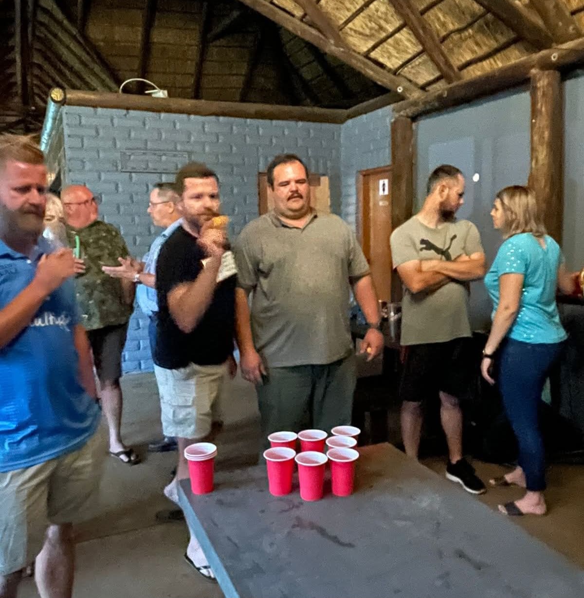 A group of friends gathered around a table in a thatched room