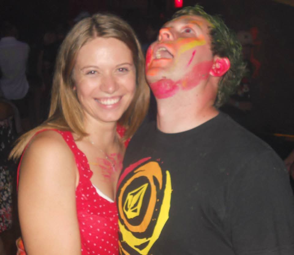 Angelo covered in colourful powder paint laughing with a friend at a party