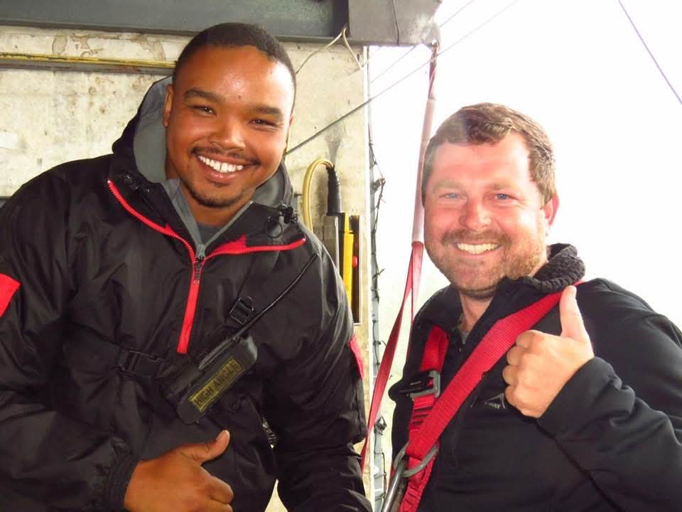 Angelo and his instructor smiling and giving a thumbs-up on the bungy platform before the jump