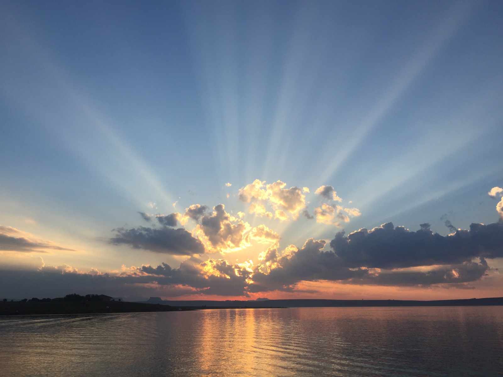A golden sunset over the lake with sunbeams breaking through cloud