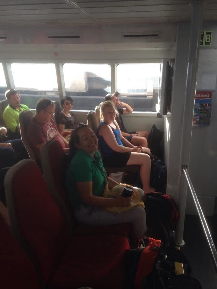 Family seated together inside a ferry with the coastline visible through the windows