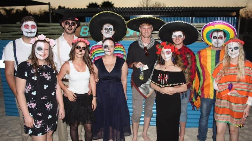 A group of friends in skeleton face paint and sombreros at a fancy-dress party