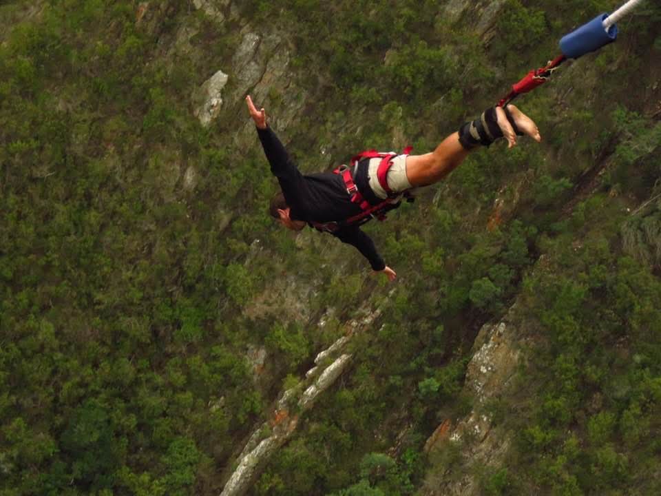 Angelo upside down beneath the bungy cord with one arm reaching up