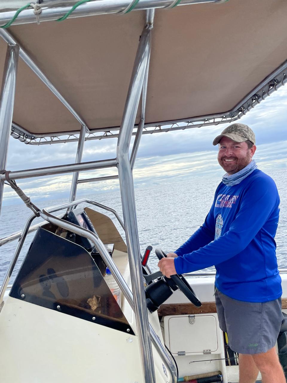 Angelo smiling at the helm of a boat on open water