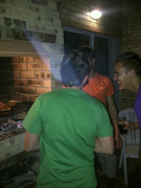 Friends laughing together around the braai on a brick patio at night