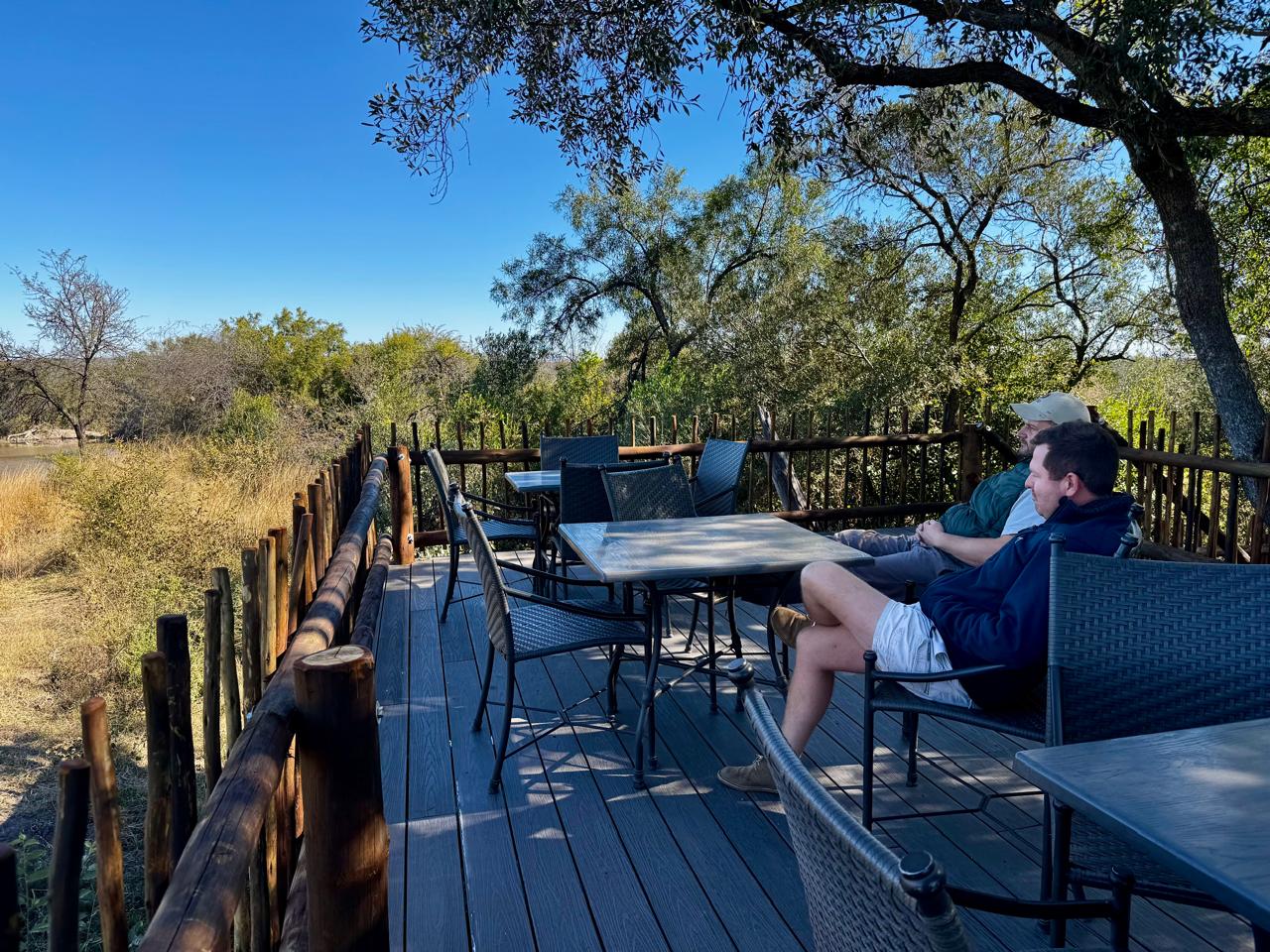 Two friends relaxing on a wooden deck overlooking the river