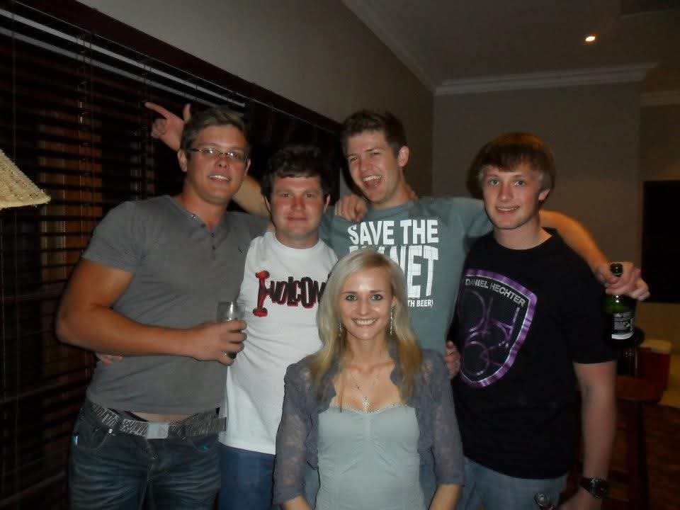 Five friends posing and laughing together indoors at a house party