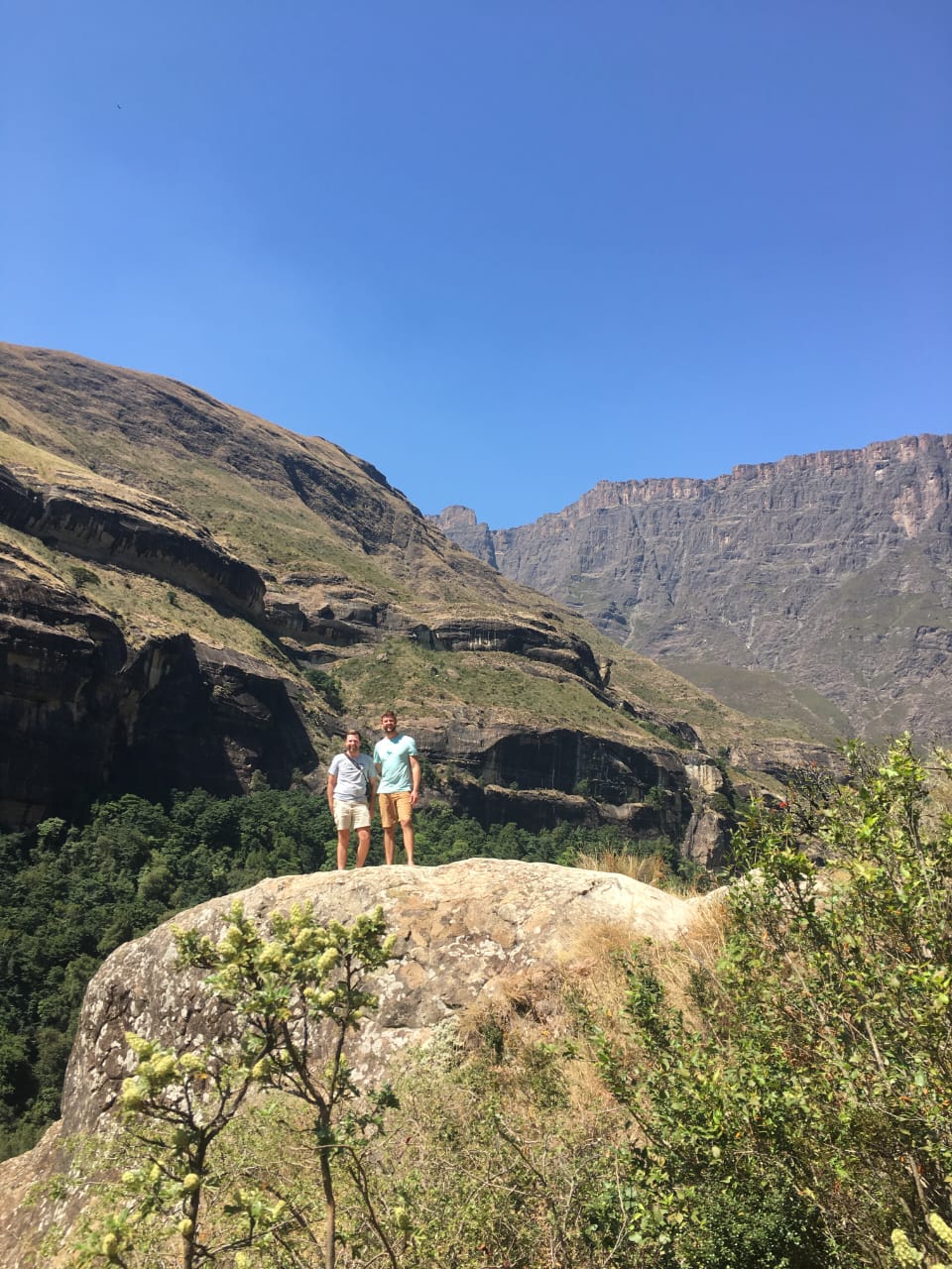 Angelo and a friend standing on a rock below the great cliff faces