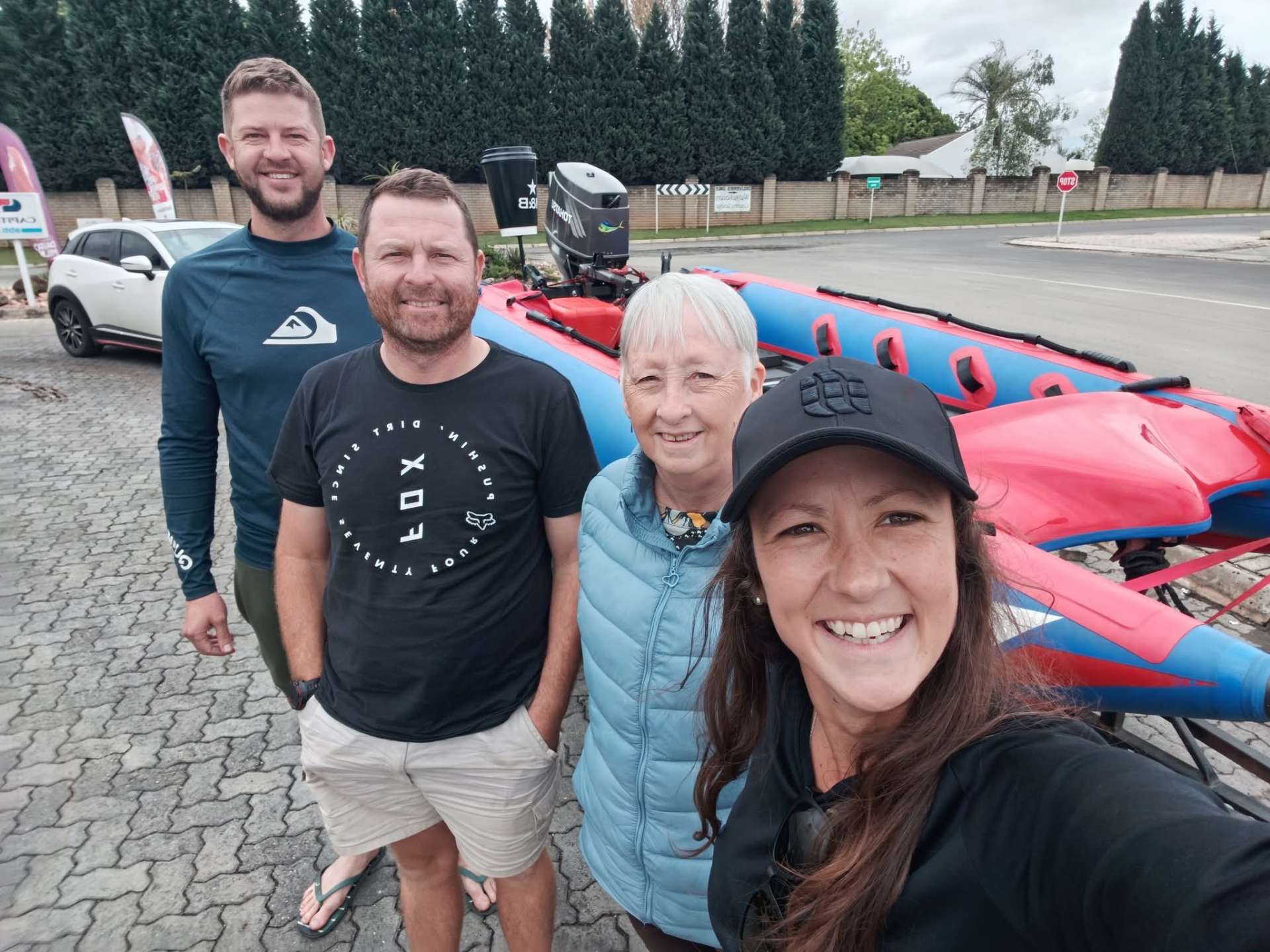 Angelo and friends smiling beside a racing inflatable boat loaded on a trailer