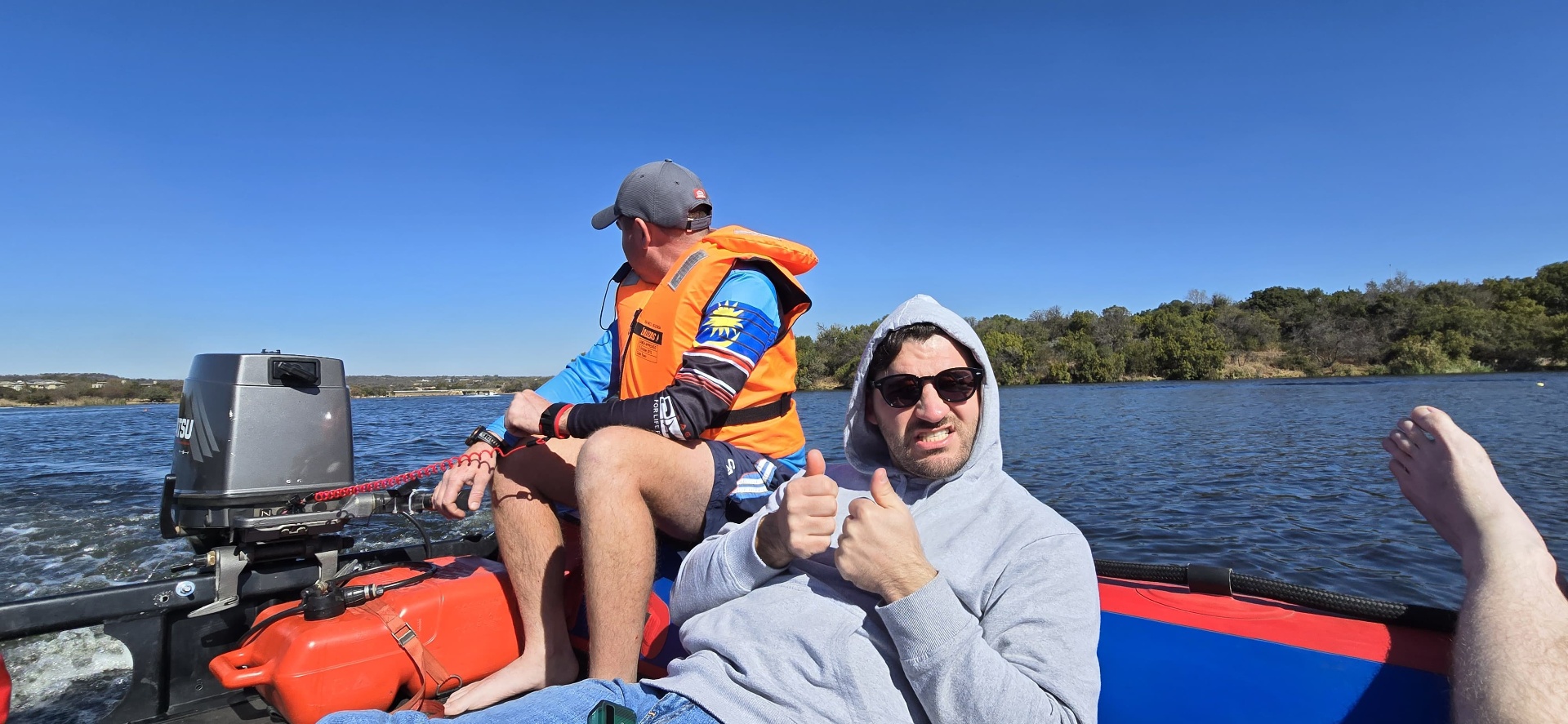 Friends on a boat on the river giving thumbs up