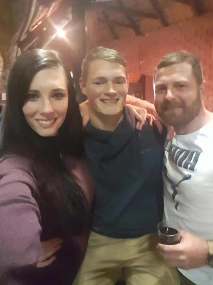 Angelo smiling in a selfie with two family members at night