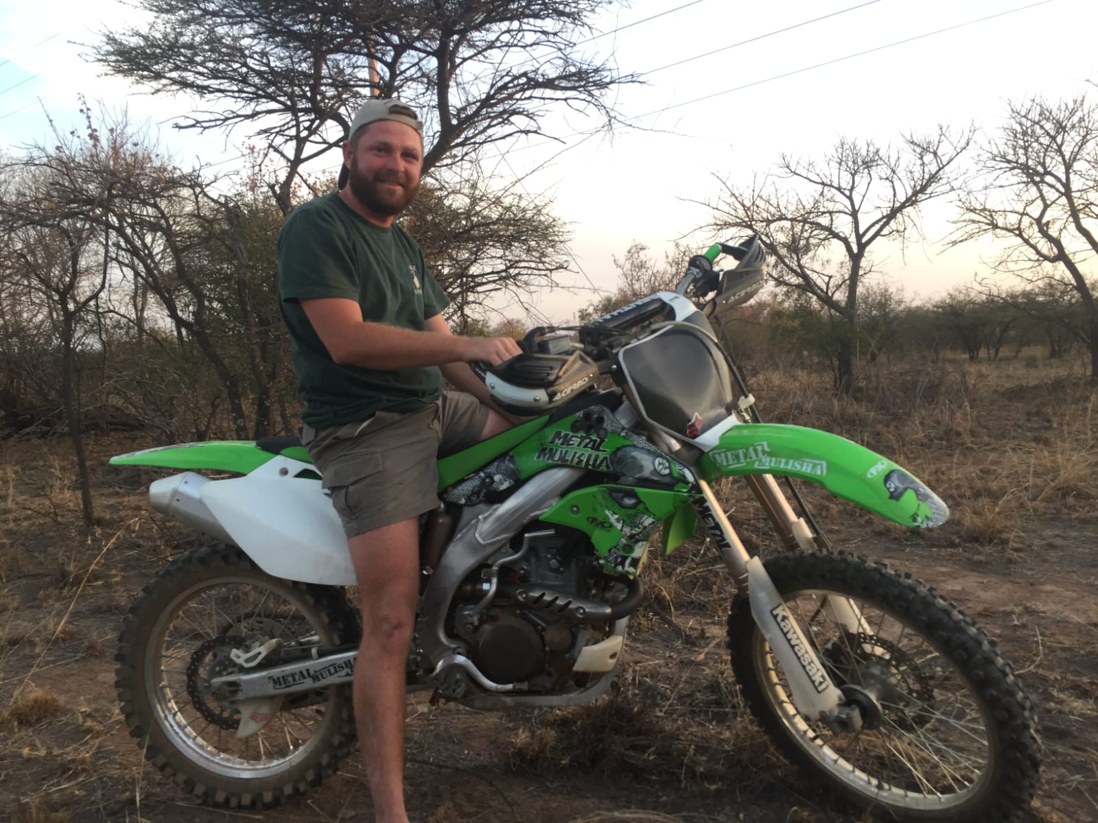 Angelo with his green dirt bike in the bushveld at dusk