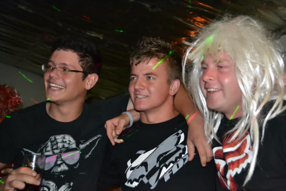 Three friends laughing together under the party lights