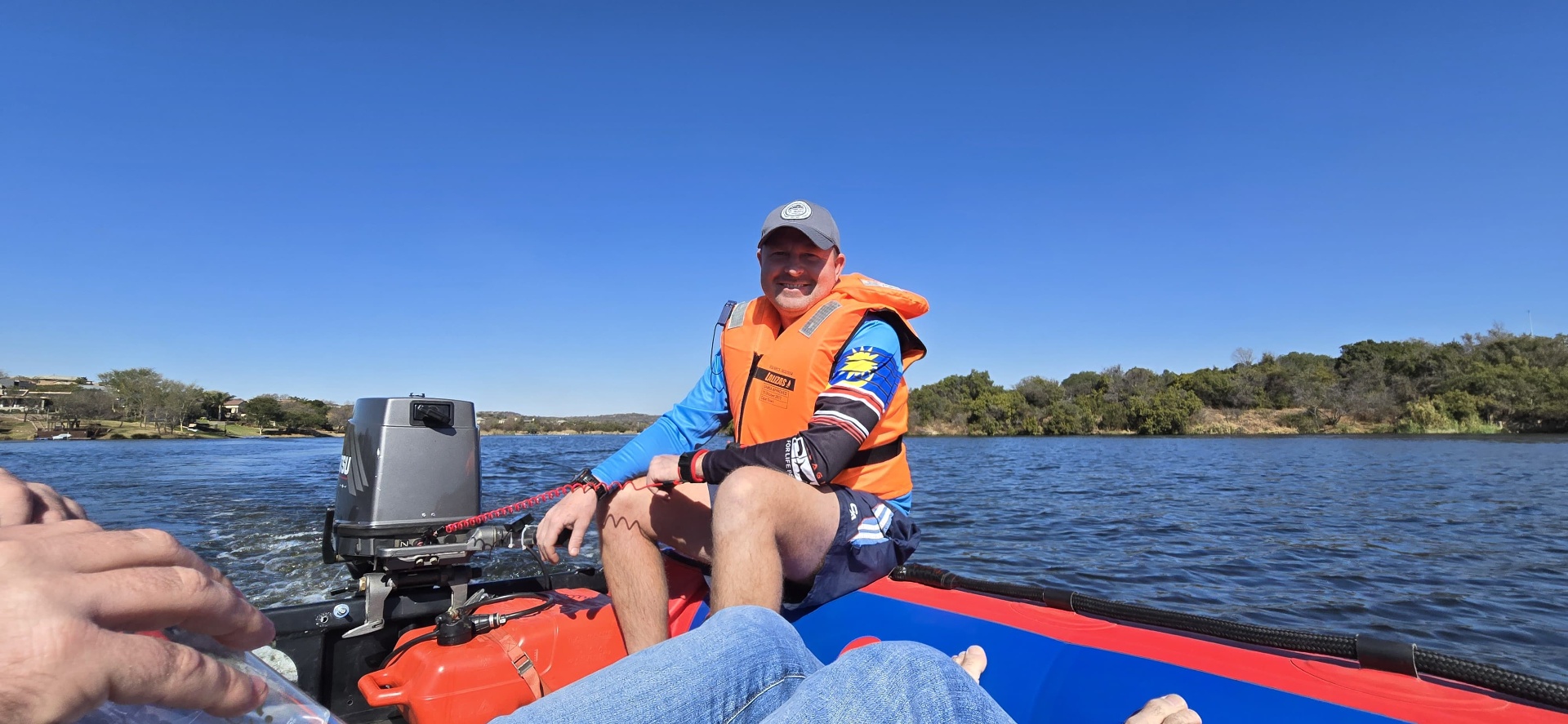 Angelo sitting on an inflatable boat crossing a blue lake