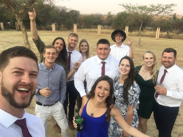 A group of friends in formal wear at a celebration outdoors at dusk