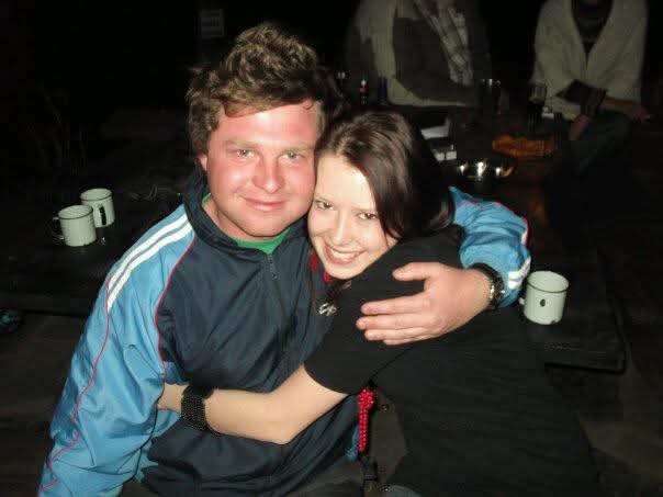 Angelo embracing a friend at a night-time campfire gathering